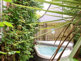 A garden with a hot tub and surrounding plants at Sunset Cottage in Swimbridge near Barnstaple