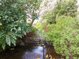 A garden with a pond and water fountain at Sunset Cottage in Swimbridge near Barnstaple