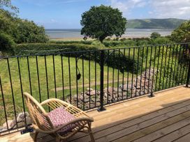A balcony with a chair and a view of the garden at Worthy Barn in Porlock Weir