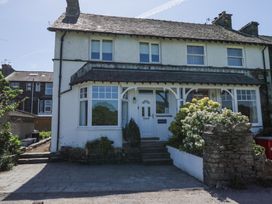 A white two-story semi-detached house with a front garden and paved driveway at Boundary House in Windermere