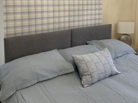 A bed with a gray headboard and blue bedding at Woods Cottage in Usk