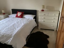 A bedroom with a bed and dresser at Woods Cottage, Usk