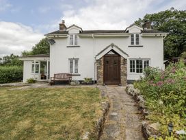 A house with a wooden door and a garden at Woods Cottage in Kingcoed near Raglan