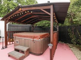 A hot tub under a wooden gazebo in an outdoor area at Woods Cottage near Raglan