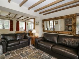A living room with leather sofas and a mirror at Woods Cottage near Raglan