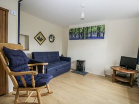 A living room with a sofa bed and rocking chair at Woods Cottage near Raglan