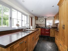 A kitchen with wooden cabinets and a red oven at Woods Cottage Kingcoed near Raglan