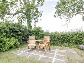 An outdoor space with wooden chairs on a stone patio at Woods Cottage near Raglan