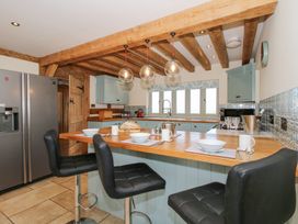 A kitchen with a wooden countertop and black bar stools at Cuckoo Pen Cottage in Eastham near Tenbury Wells