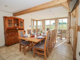 A dining room with a wooden table set for eight and a wooden cabinet at Cuckoo Pen Cottage in Eastham near Tenbury Wells