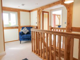 A hallway with wooden railings blue armchair and a window with a vase at Cuckoo Pen Cottage in Eastham near Tenbury Wells