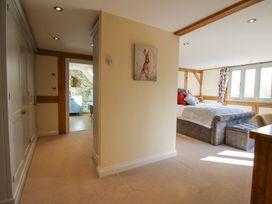 A bedroom with a visible bed and a hallway leading to a bathroom with floral wallpaper at Cuckoo Pen Cottage in Eastham near Tenbury Wells