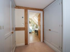 A hallway with built in closets and a doorway leading to a bathroom with a floral wallpaper at Cuckoo Pen Cottage Eastham near Tenbury Wells