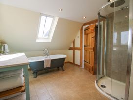 A bathroom with a clawfoot bathtub under a skylight a glass shower enclosure a wooden door and a counter with towels at Cuckoo Pen Cottage in Eastham near Tenbury Wells