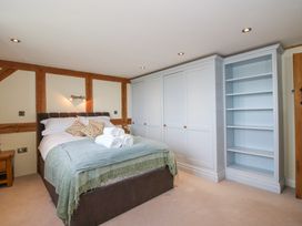 A bedroom with a bed with folded towels and pillows and a large white wardrobe with shelves at Cuckoo Pen Cottage Eastham near Tenbury Wells