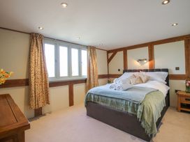 A bedroom with a bed with rolled towels and cushions beside wooden furniture at Cuckoo Pen Cottage in Eastham near Tenbury Wells