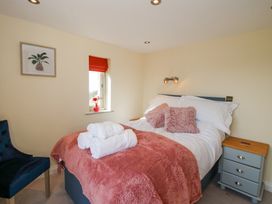 A bedroom with a bed with pink pillows and blanket bedside table and window with a red blind at Cuckoo Pen Cottage Eastham near Tenbury Wells
