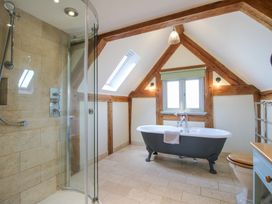 A bathroom with a freestanding bathtub shower enclosure toilet and wooden beams at Cuckoo Pen Cottage in Eastham near Tenbury Wells