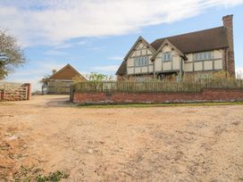 A two-story house with a tiled roof a brick wall and wooden fence in front and a detached garage to the left at Cuckoo Pen Cottage Eastham near Tenbury Wells