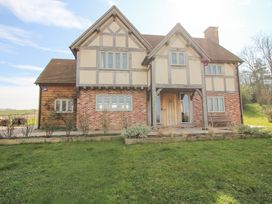 The exterior of a two-story house with timber framing and brick walls surrounded by a lawn at Cuckoo Pen Cottage in Eastham near Tenbury Wells