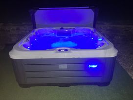 An outdoor hot tub with blue lights in water at Cuckoo Pen Cottage in Eastham near Tenbury Wells