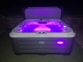 A hot tub with purple lights on a grass surface at Cuckoo Pen Cottage in Eastham near Tenbury Wells
