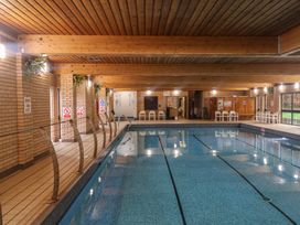 An indoor pool with safety signs and seating at Tri-Star House Charmouth
