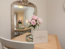 A dining room with a table and flowers at Seashell Sands in Appledore
