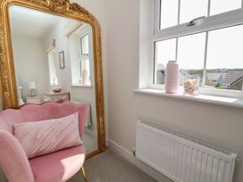 A living room with a pink chair and mirror at Seashell Sands in Appledore