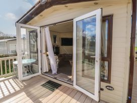 An open glass door leading to a deck with a round glass table and stools at A La Mer in Paignton
