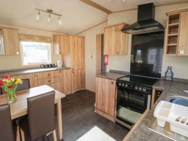 A kitchen with wood cabinets a black oven a sink with a dish rack and a table with chairs and flowers at A La Mer in Paignton