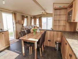 A kitchen and dining area with wooden cabinets a dining table with chairs and a vase of flowers at A La Mer in Paignton
