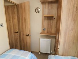 A bedroom with two single beds a radiator a wooden wardrobe and shelving at A La Mer in Paignton