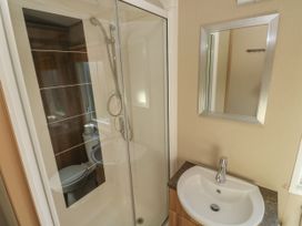 A bathroom with a shower enclosure a sink with a faucet and a mirror at A La Mer in Paignton