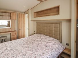 A bedroom with a bed with patterned bedding a wooden desk with mirror and stool at A La Mer in Paignton
