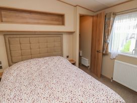 A bedroom with a bed a window with curtains and an open door at A La Mer in Paignton