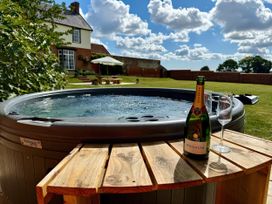 A hot tub with a champagne bottle and glass on a wooden table at Knights Farm in Harkstead
