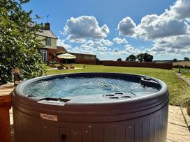 A hot tub with a wine bottle and glass in the garden at Knights Farm in Harkstead