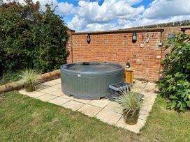 A hot tub with a side table and champagne bottle at Knights Farm in Harkstead