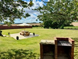 A garden with a picnic table and barbecue at Knights Farm in Harkstead