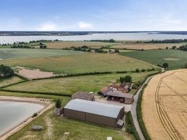 An aerial view of a farm with fields and a lake at Knights Farm Harkstead
