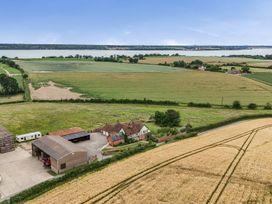 An aerial view of a farmhouse and barn near a lake at Knights Farm Harkstead