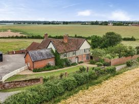 An exterior view of a house with a field and trees at Knights Farm in Harkstead