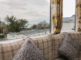 A close up of a sofa with patterned cushions by a window showing mobile homes and trees outside at Ocean View in Combe Martin