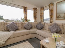 A beige corner sofa with patterned cushions and yellow floral curtains in a living room at Ocean View in Combe Martin