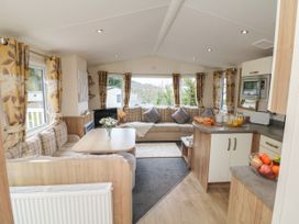 A living area with a dining table sofa cushions and kitchen counter at Ocean View in Combe Martin
