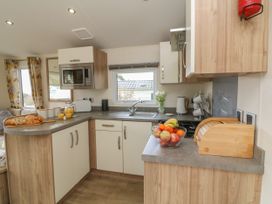 A kitchen with a microwave toaster bread board fruit bowl and sink at Ocean View in Combe Martin