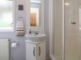 A bathroom with a sink and cabinet a mirror and a glass shower enclosure at Ocean View in Combe Martin
