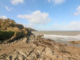 A rocky coastline with trees on cliffs and waves breaking at Ocean View in Combe Martin