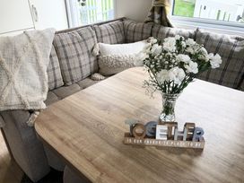 A dining area with a wooden table a vase of white flowers and a checkered sofa with cushions at Ocean View in Combe Martin